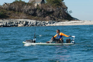 Man fishing from a green Sea Eagle iSUP with a swivel seat, two Scotty rod holders, and a trolling motor.