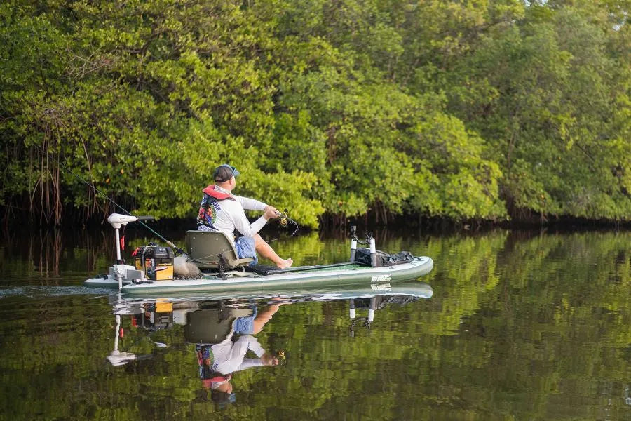 Green Sea Eagle iSUP with a swivel seat fishing rig, Scotty rod holders, and a man fishing.