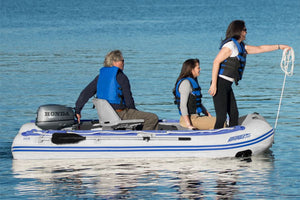 Three people in a white and blue Sea Eagle inflatable sport runabout with a Honda outboard motor and a gray locking swivel seat.