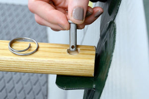 Hand inserting a silver pin into a light ash wood Sea Eagle canoe seat.