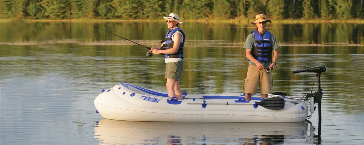 Two men fishing from a white and blue Sea Eagle 9 inflatable boat with an electric motor on a calm lake.