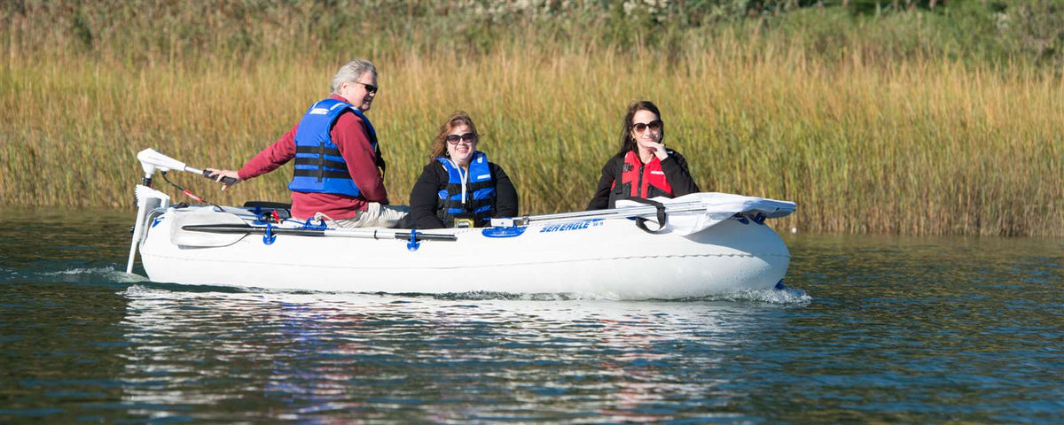 White Sea Eagle 9 inflatable boat with three people wearing life vests, powered by an electric motor.
