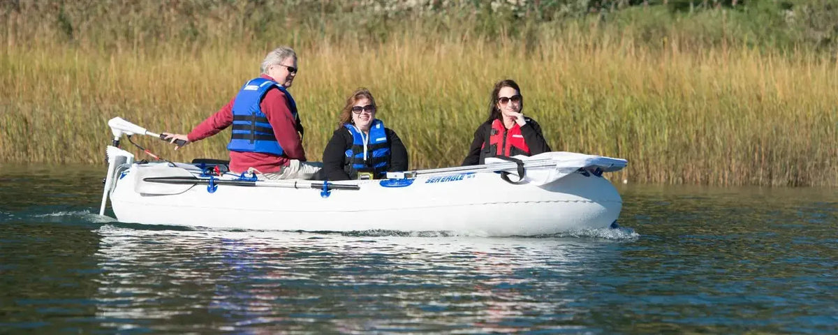 White Sea Eagle 9 inflatable boat with three people wearing life vests, powered by an electric motor.