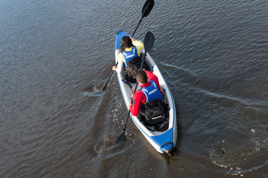 Two people in a blue and white inflatable kayak with black Tall Back Kayak Seats and paddles.