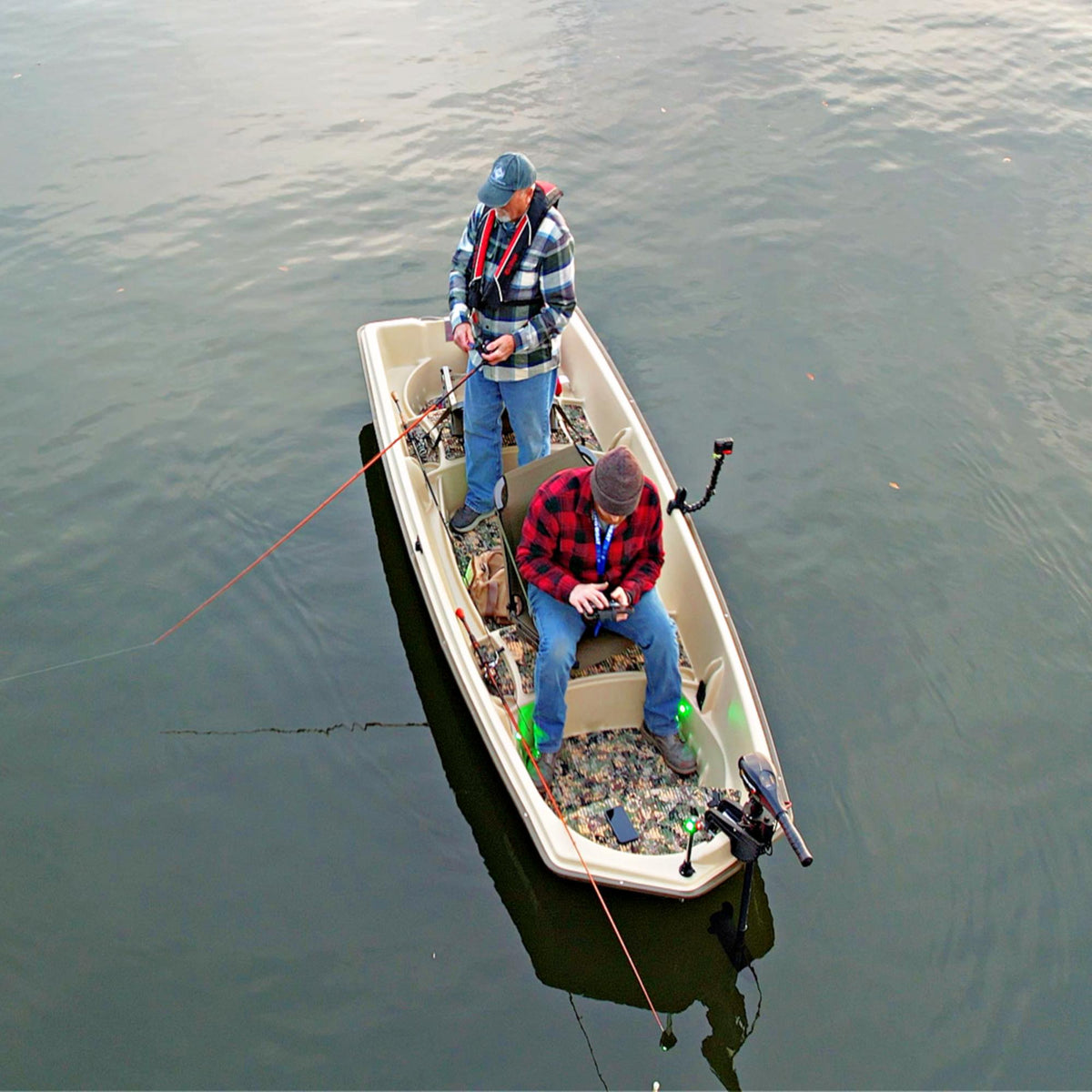Two men fishing from a tan Sun Dolphin American 12 boat with a camouflage floor kit installed.
