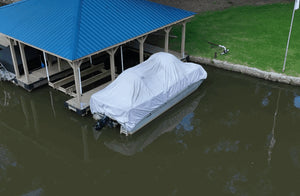 White boat cover supported by SwellUP system, keeping it taut under a blue boathouse roof.