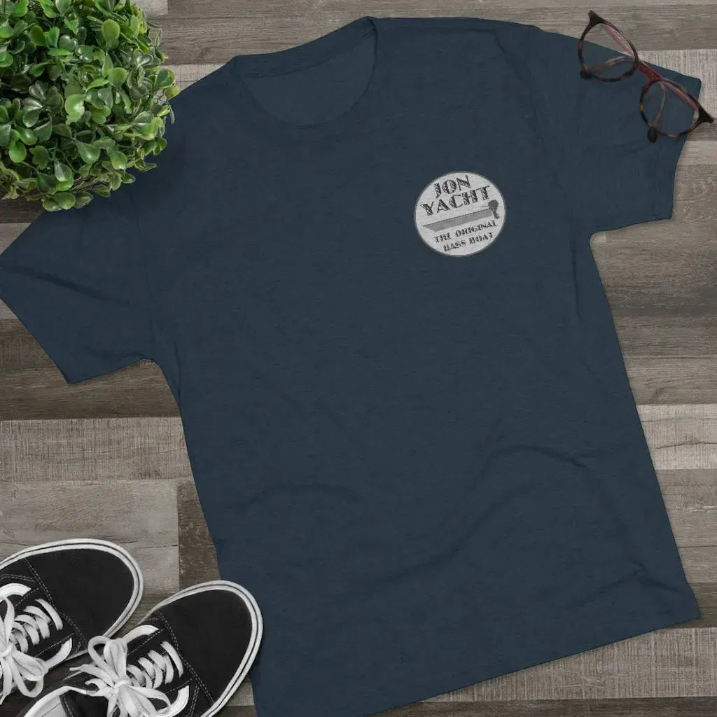 Navy tri-blend tee with "Jon Yacht The Original Bass Boat" logo, black sneakers, plant, and glasses.