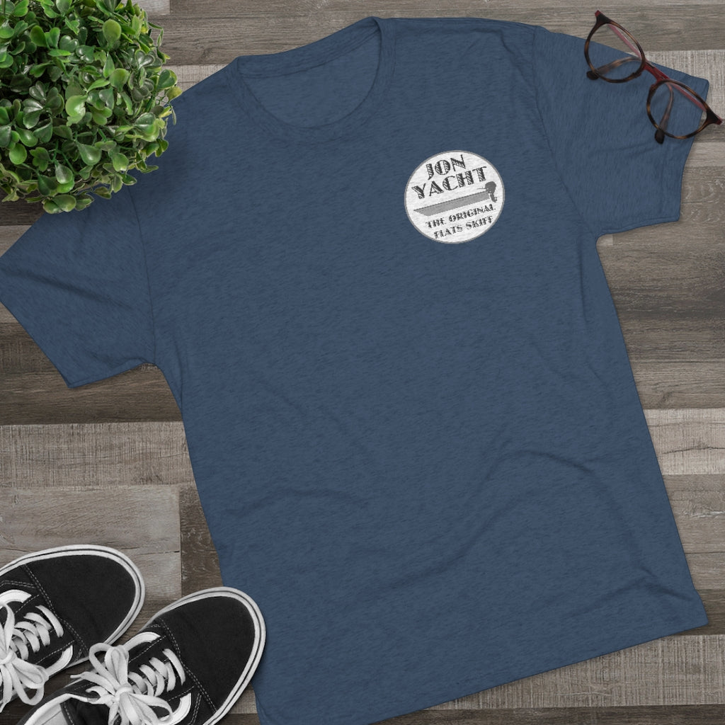 Navy blue "Jon Yacht The Original Flats Skiff" graphic tee on a wooden surface with sneakers and glasses.