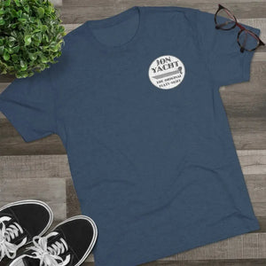 Navy blue "Jon Yacht The Original Flats Skiff" graphic tee on a wooden surface with sneakers and glasses.
