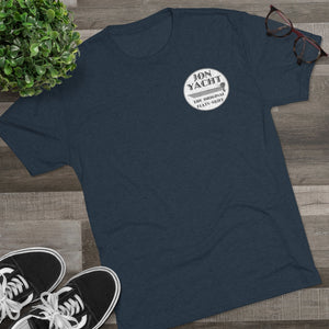 Navy blue "Jon Yacht The Original Flats Skiff" t-shirt with a white circular logo on a wooden surface.