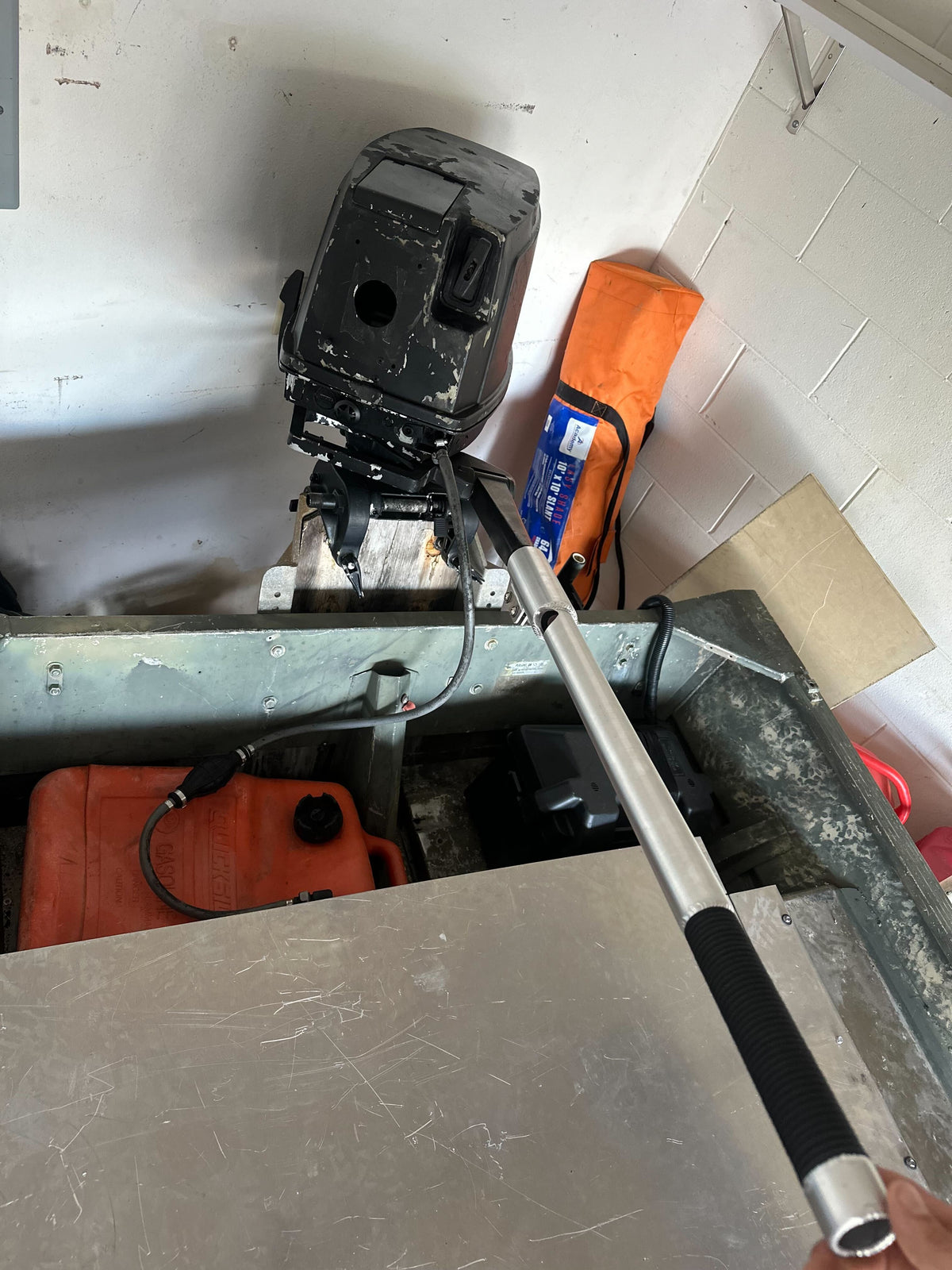 Silver aluminum X-LONG tiller extension handle with black grip on an outboard motor in a boat.