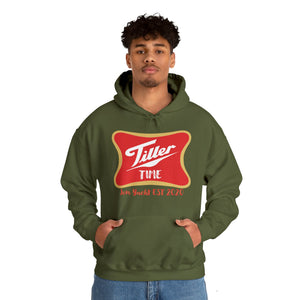 Man wearing an olive green "Tiller Time" hoodie with a red and gold graphic, featuring a kangaroo pocket.