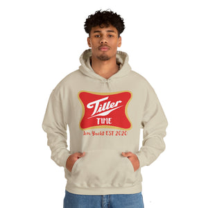 Man in a beige Tiller Time hoodie with a red and gold graphic, kangaroo pocket, and matching drawstring.