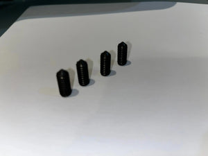 Four small black threaded pins for marking drill holes, arranged diagonally on a white surface.