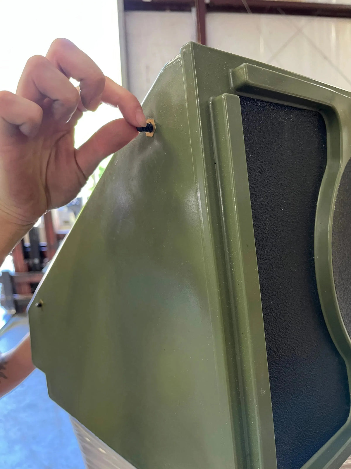 Hand inserting a black pin into a mounting hole on a dark green Universal Jon Boat Tiller Console.