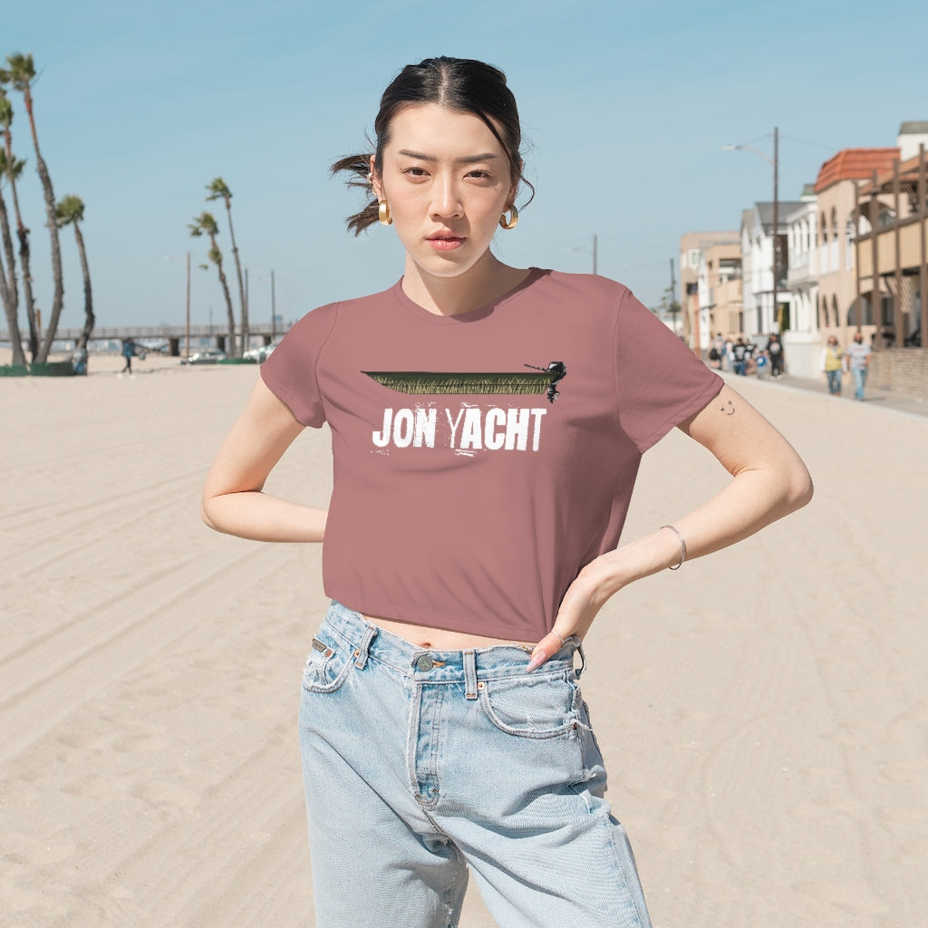 Woman in a flowy, modest crop tee with a "Jon Yacht" boat graphic on a beach.