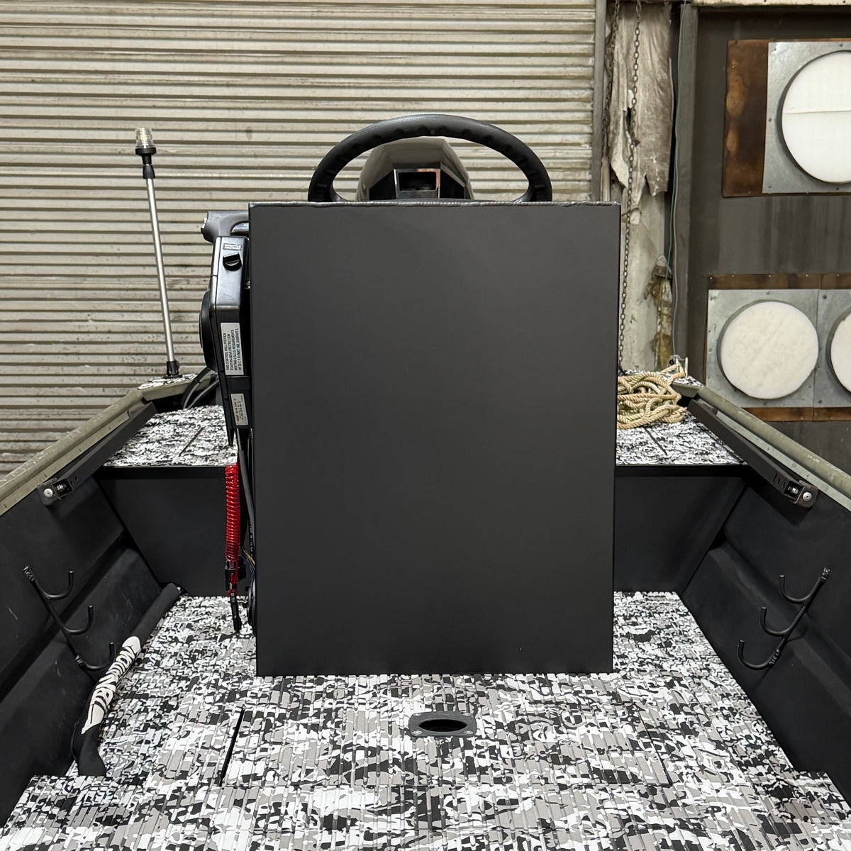 Black rectangular object on a boat deck with a steering wheel in the background