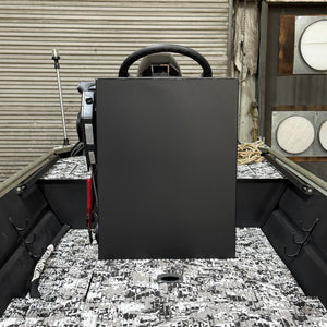 Black rectangular object on a boat deck with a steering wheel in the background