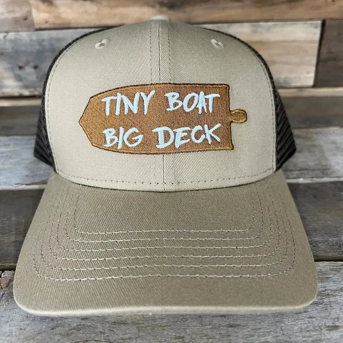 Tan and brown trucker hat with "TINY BOAT BIG DECK" embroidered on a wooden paddle design.