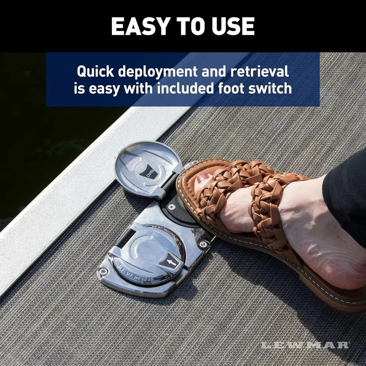 Lewmar Venta electric pontoon anchor winch foot switch on a boat deck, pressed by a foot in a brown sandal.