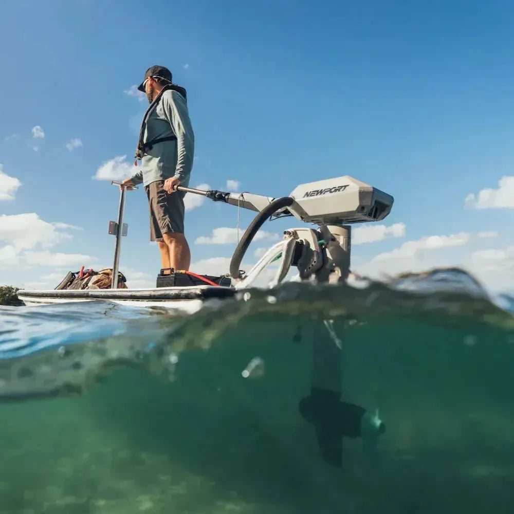 Man on a paddleboard with a gray Newport NT600 6hp electric outboard motor, propeller submerged.