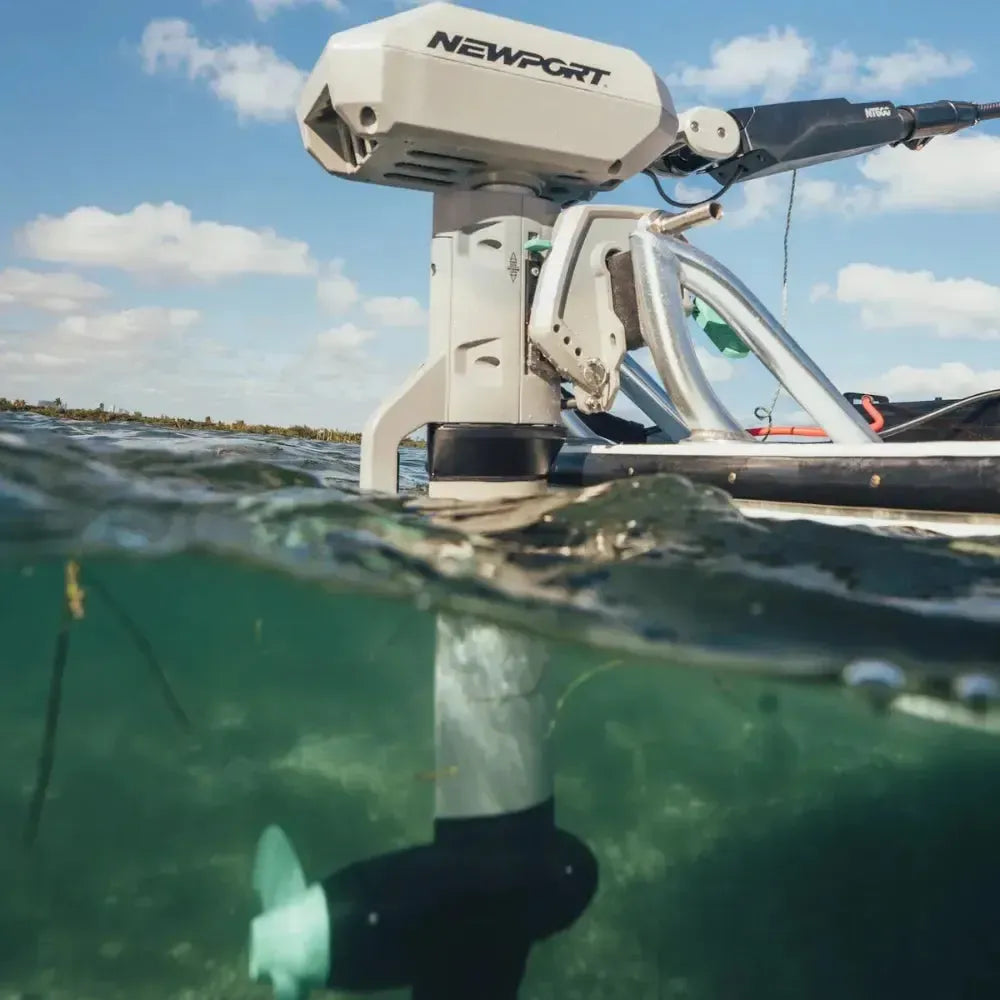 Newport NT600 6hp electric outboard motor, light gray, mounted on a boat with propeller submerged in clear water.