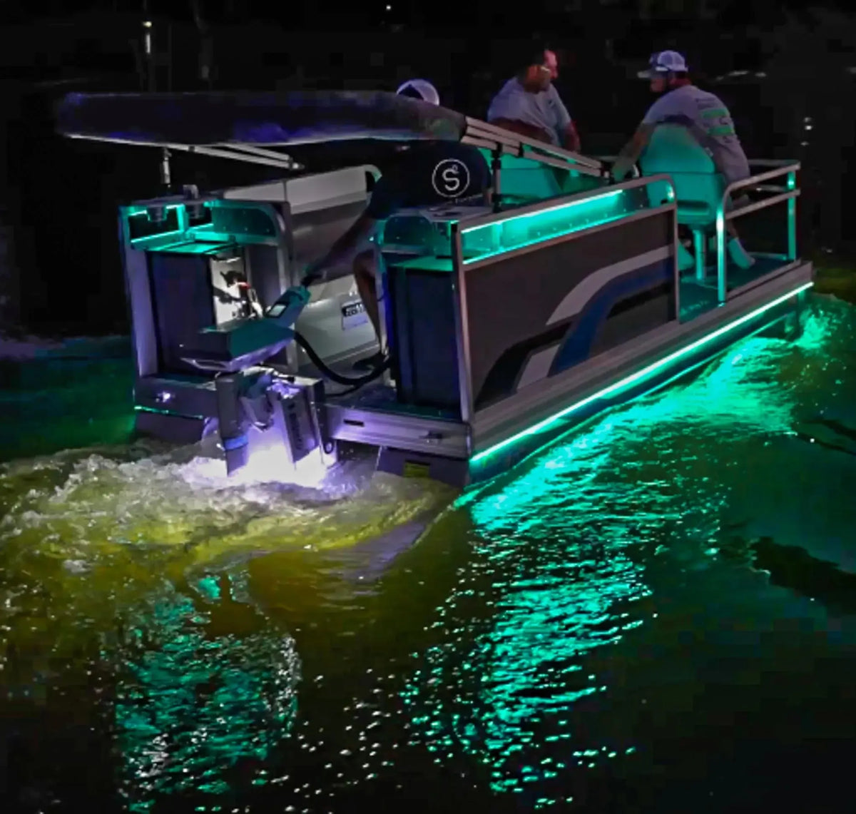 Pontoon boat at night with vibrant green Plashlight RGBW flexible LED strips illuminating the deck and water.