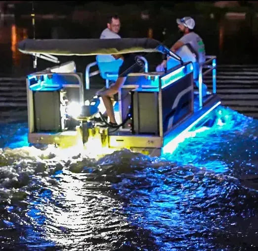 Pontoon boat at night with bright blue and yellow RGBW Plashlight strips illuminating the water.