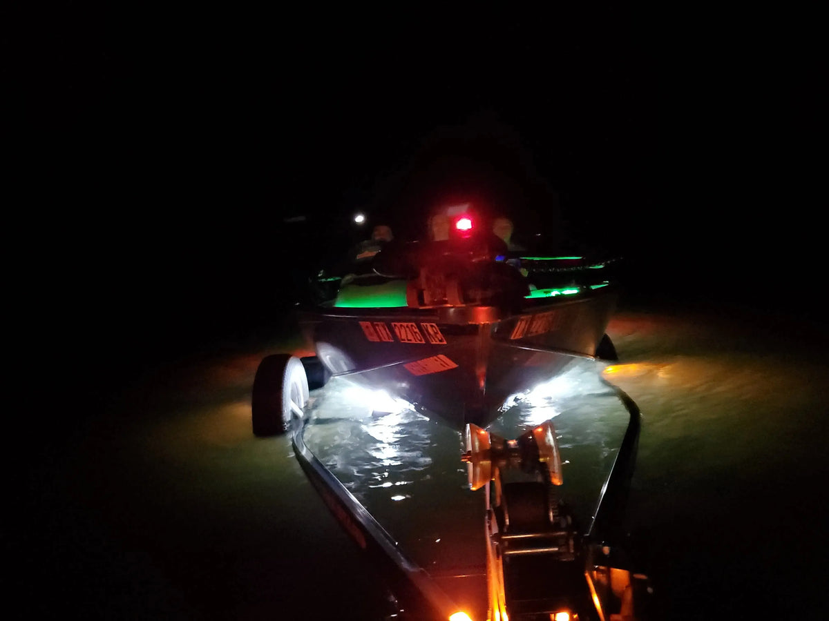 Boat launching at night with bright white and green Plashlight LED strips illuminating the water.