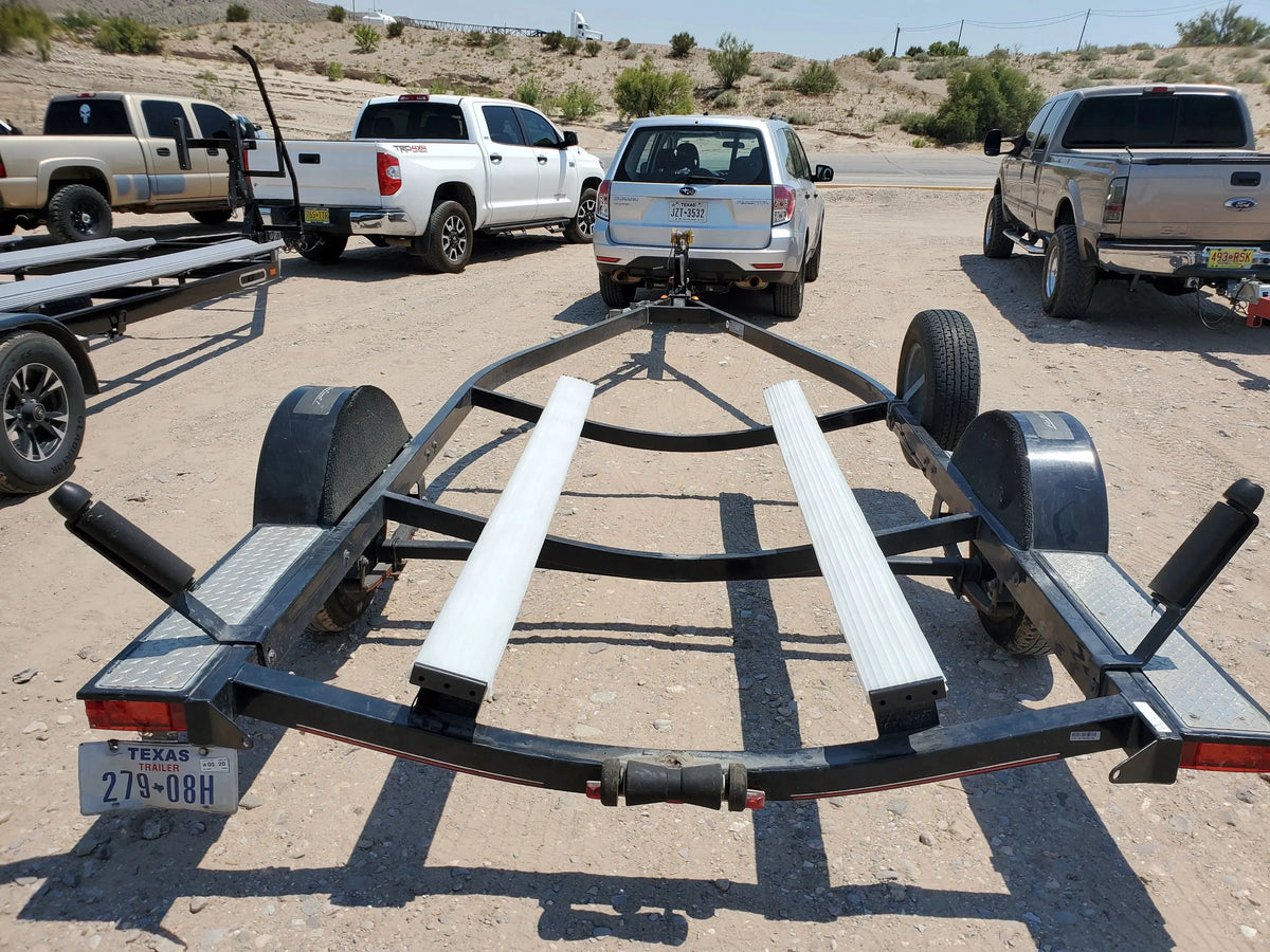 Black boat trailer with two white Plashlight bunk board LED light strips in a desert parking lot.