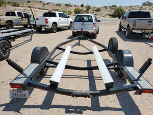 Black boat trailer with two white Plashlight bunk board LED light strips in a desert parking lot.