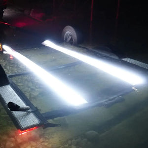 Two bright white Plashlight LED strips illuminating underwater bunk boards on a boat trailer at night.