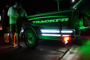Green LED light strips illuminate a Tracker boat on a trailer at night.