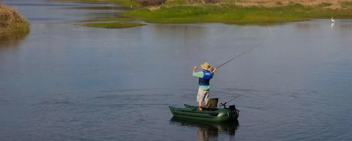 Man fly fishing from a compact Hunter Green Sea Eagle 285 frameless inflatable pontoon boat on a calm lake.