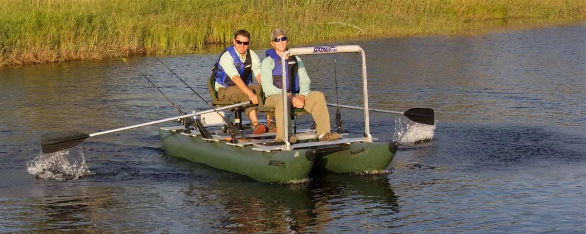 Two men fishing from a dark hunter green Sea Eagle 375fc FoldCat inflatable pontoon boat with oars.
