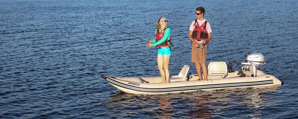 Two people fishing from a tan Sea Eagle 437ps PaddleSki inflatable catamaran with a Honda motor.