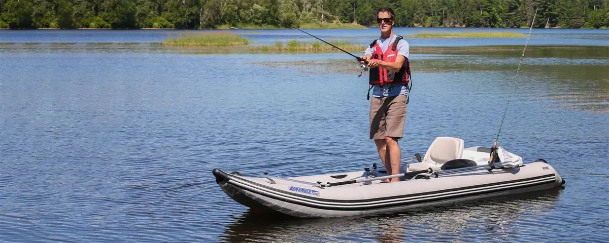 Man fishing from a gray Sea Eagle 437ps PaddleSki inflatable catamaran boat on a lake.