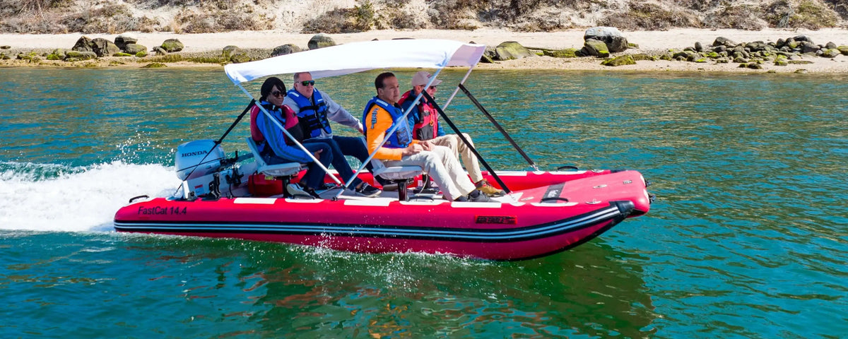 Red Sea Eagle FastCat14 inflatable catamaran with four people, a white bimini top, and Honda outboard motor on water.