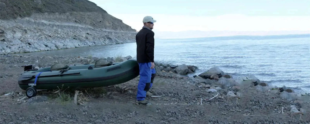 Hunter Green Sea Eagle Stealth Stalker 10 inflatable fishing boat on rocky shore with man.