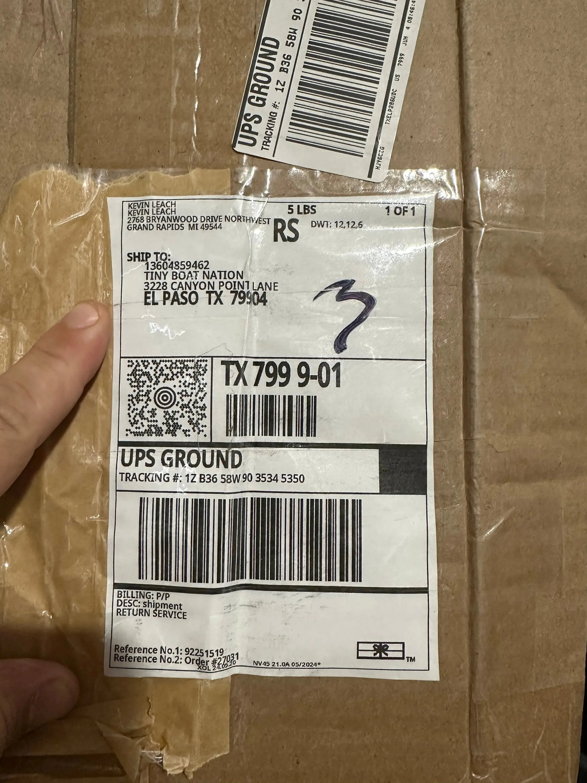 Hand holding a UPS shipping label on a cardboard box