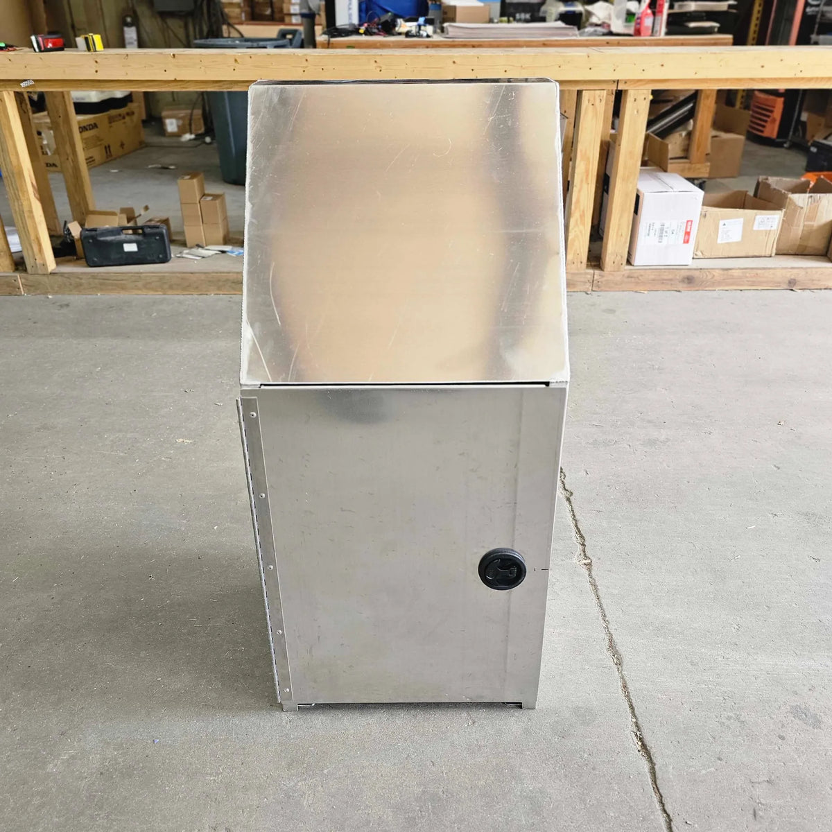 Metallic appliance on a concrete floor with a workshop background