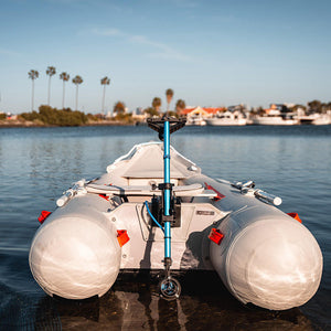 Inflatable boat with large white pontoons on a body of water with palm trees in the background.