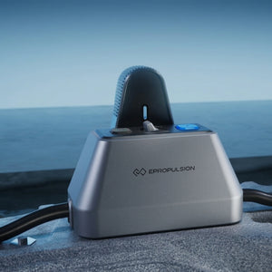 ePropulsion kLite 7500 outboard motor device with a metallic silver base and dark gray curved top, shown outdoors with the ocean in the background.
