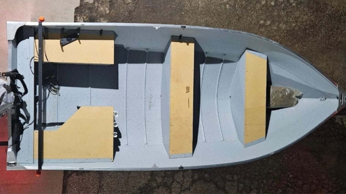 Top-down view of a boat with yellow padding on a concrete surface