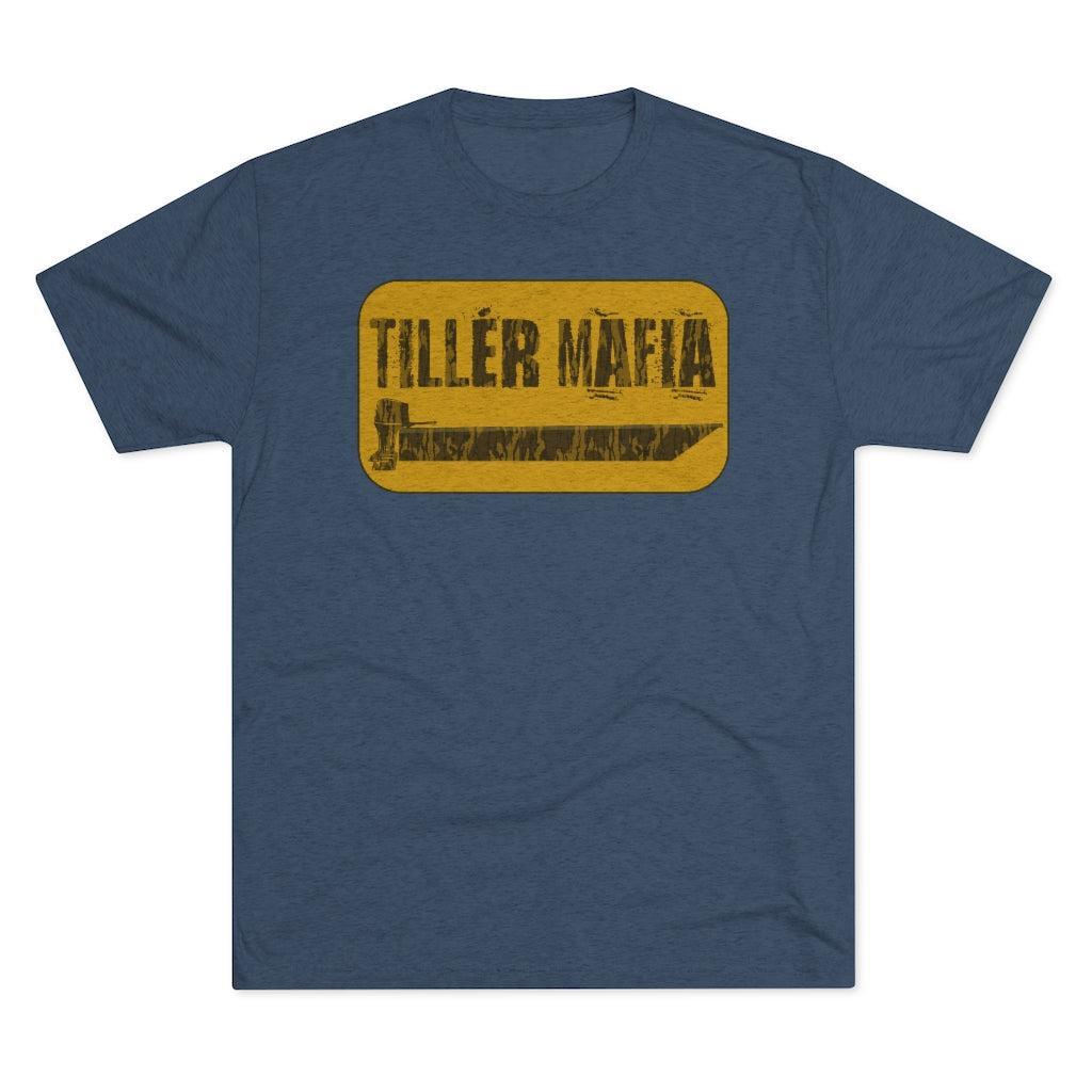 A heathered blue crewneck t-shirt featuring a distressed yellow rectangular graphic on the chest with the text 'TILLÉR MAFIA' and a small illustration.