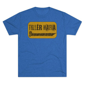 A heather blue short-sleeve crewneck t-shirt featuring a distressed yellow rectangular graphic on the chest with the text 'TILLÉR MAFIA' and a small truck illustration.