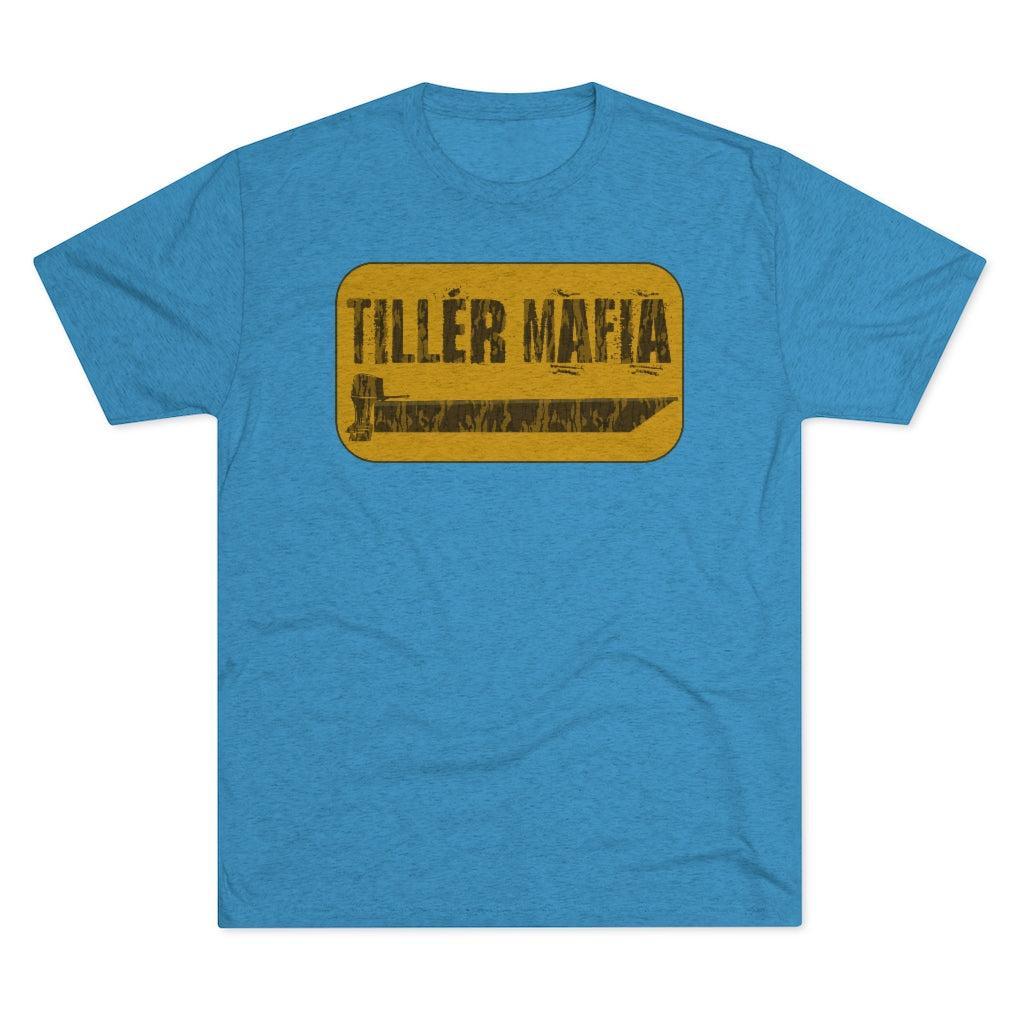 A heather blue short-sleeve t-shirt with a distressed yellow rectangular graphic on the chest that reads 'TILLER MAFIA' in black text.