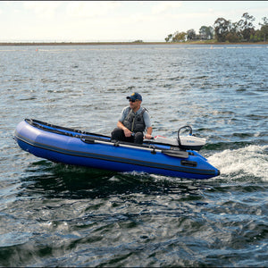 Person in a blue inflatable boat on a body of water with trees in the background