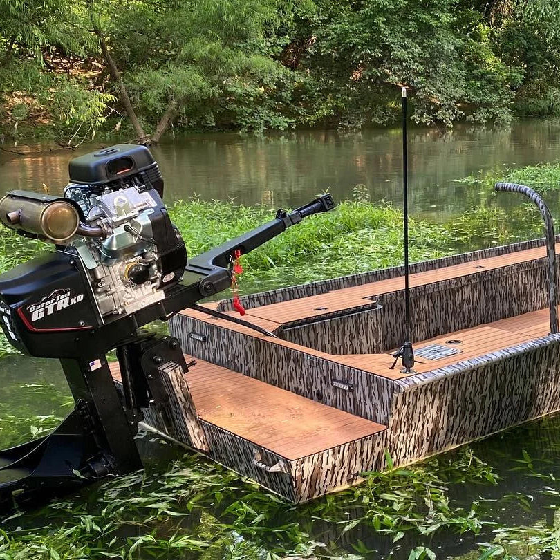 Max It Out LEDs Premier Universal LED Stern Light installed upright on a camouflage flat-bottom boat floating in a wooded waterway.