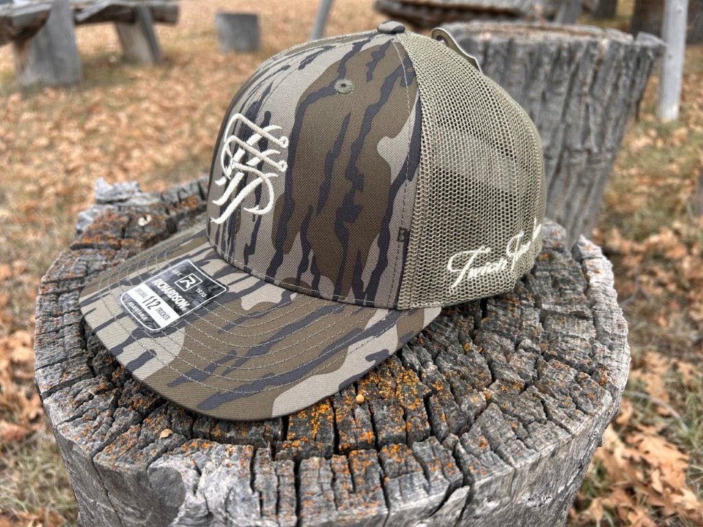 Camouflage baseball cap with mesh back on a wooden stump outdoors